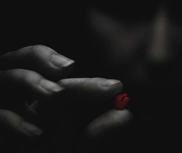 Broken red heart in the moody girl's hands