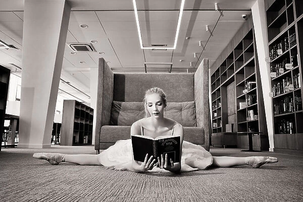 the Dreamer. ballerina on pointe shoes in the library reads a book holding it up