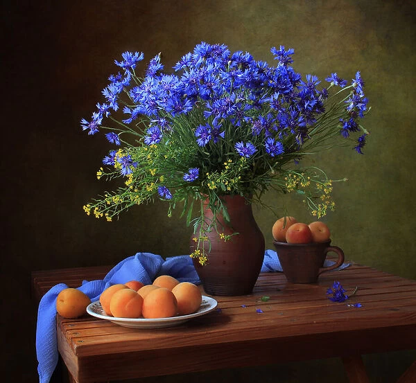 Still life with a bouquet of cornflowers and apricots