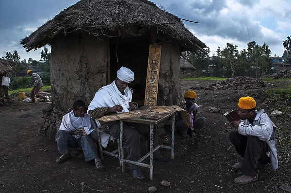 A priest is painting while some guys are praying (Lalibela - Ethiopia)