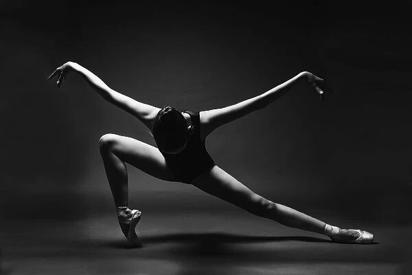 soaring. A ballerina in a pointe shoes in a lunge with her arms outstretched like wings