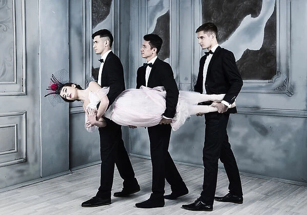 Trinity. three men in tuxedos carry a ballerina in their arms