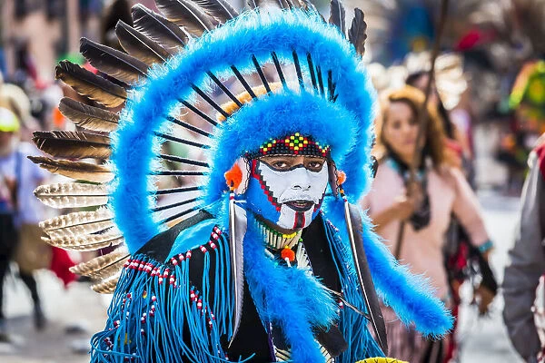 Portrait of male, indigenous tribal dancer wearing blue feathered headdress and looking at the camera in the St Michael Archangel Festival parade in San Miguel de Allende, Mexico