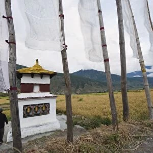 A man circumambulating a stupa with prayer flags, Punakha, Bhutan, Asia