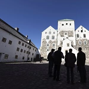 Men silhoutted against Turku Medieval Castle, Turku, Western Finland, Finland