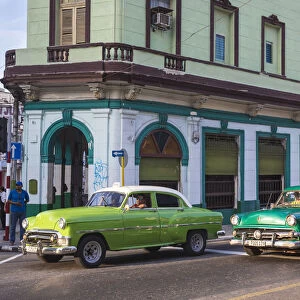 Cuba, Havana, Classic American cars passing by Bar San Juan