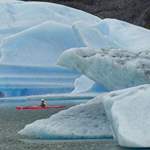 Kayaker exploring Grey Lake amid icebergs, Torres del Paine National Park, Chile