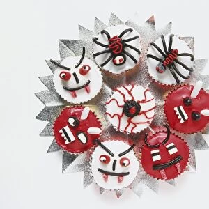 Halloween cupcakes, decorated with red, black and white icing and sweets to look like eyeballs, monster faces and spiders, view from above