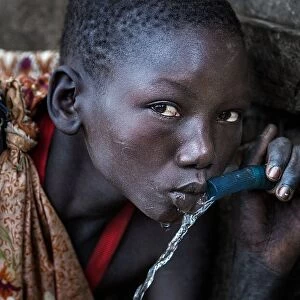 Surmi tribe girl drinking water from a tap - Ethiopia