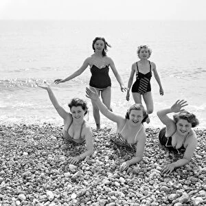 A group of friends waving during a visit to the beach in Springtime Britain Circa