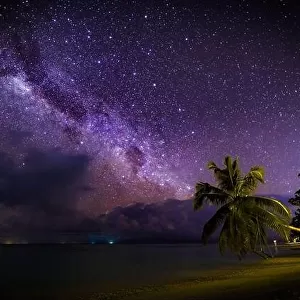 Amazing night photo with milky way, stars and bright galaxy view pattern. Milky Way over the sandy beach with palm trees