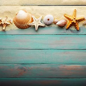Vacations and summer time concept with starfish and sea shells on a turquoise wooden table with sand